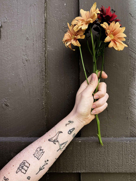 hand holding flowers and tattoo arm